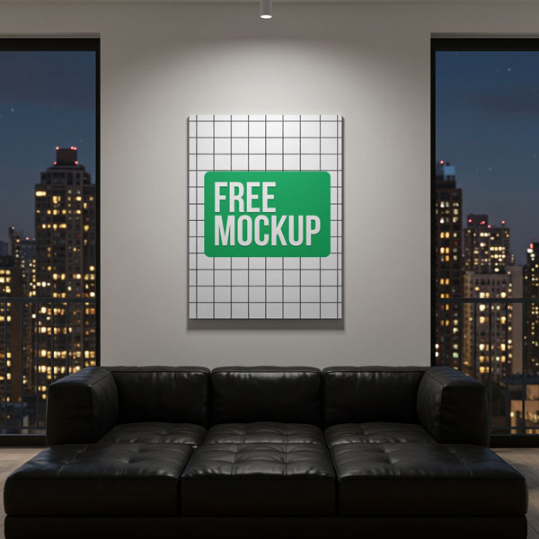 Night City View Canvas Free Mockup. A vertical canvas print with a company logo, illuminated by a spotlight, hangs on the wall of a luxury apartment. The room features a black leather sofa and large windows with a view of a city skyline at night.