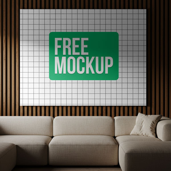 Large Canvas Over Sofa Free Mockup. A large, horizontal canvas displaying a company logo hangs on a modern wood slat wall above a light-colored sectional sofa in a stylish living room.